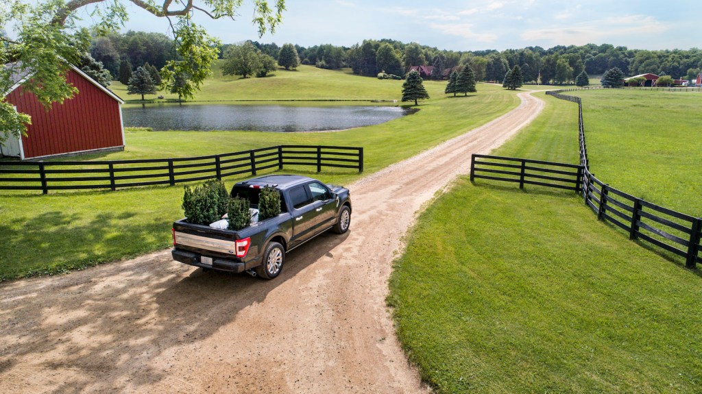 Ford F-150 half-ton pickup truck driving past a split-rail fence and into a barnyard.