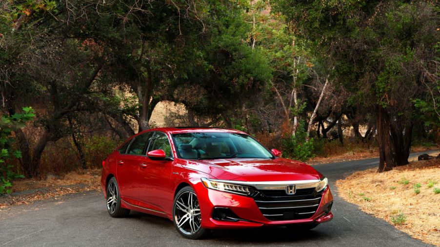 A red 2022 Honda Accord Hybrid in a wooded area.