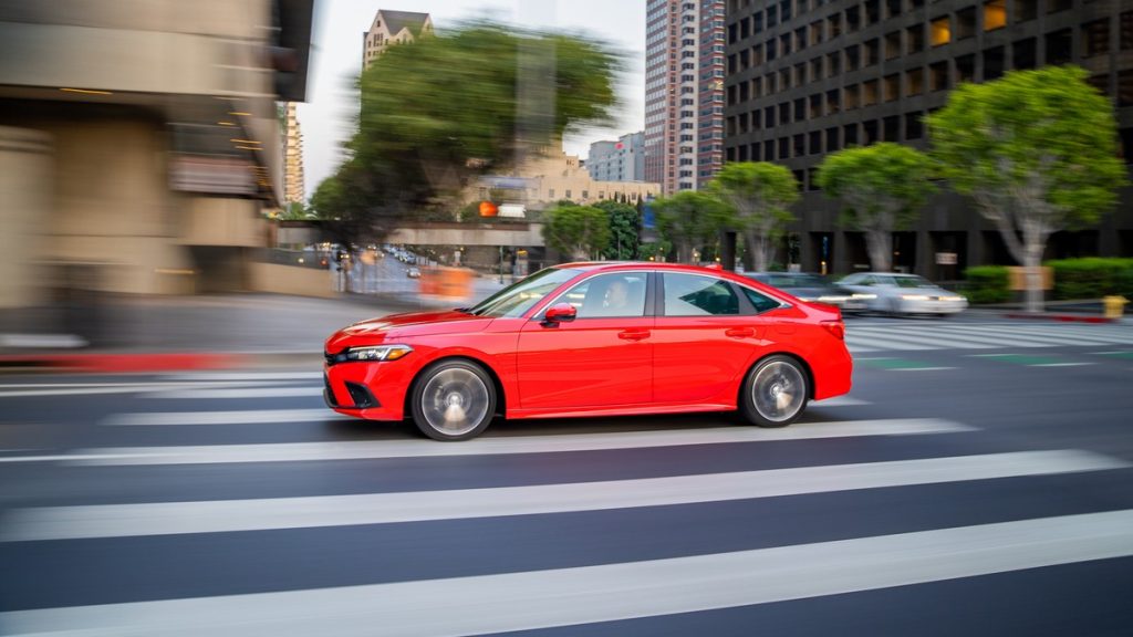 a 2022 red honda civic drives down a city street, showing off its sleek design and comfortable ride