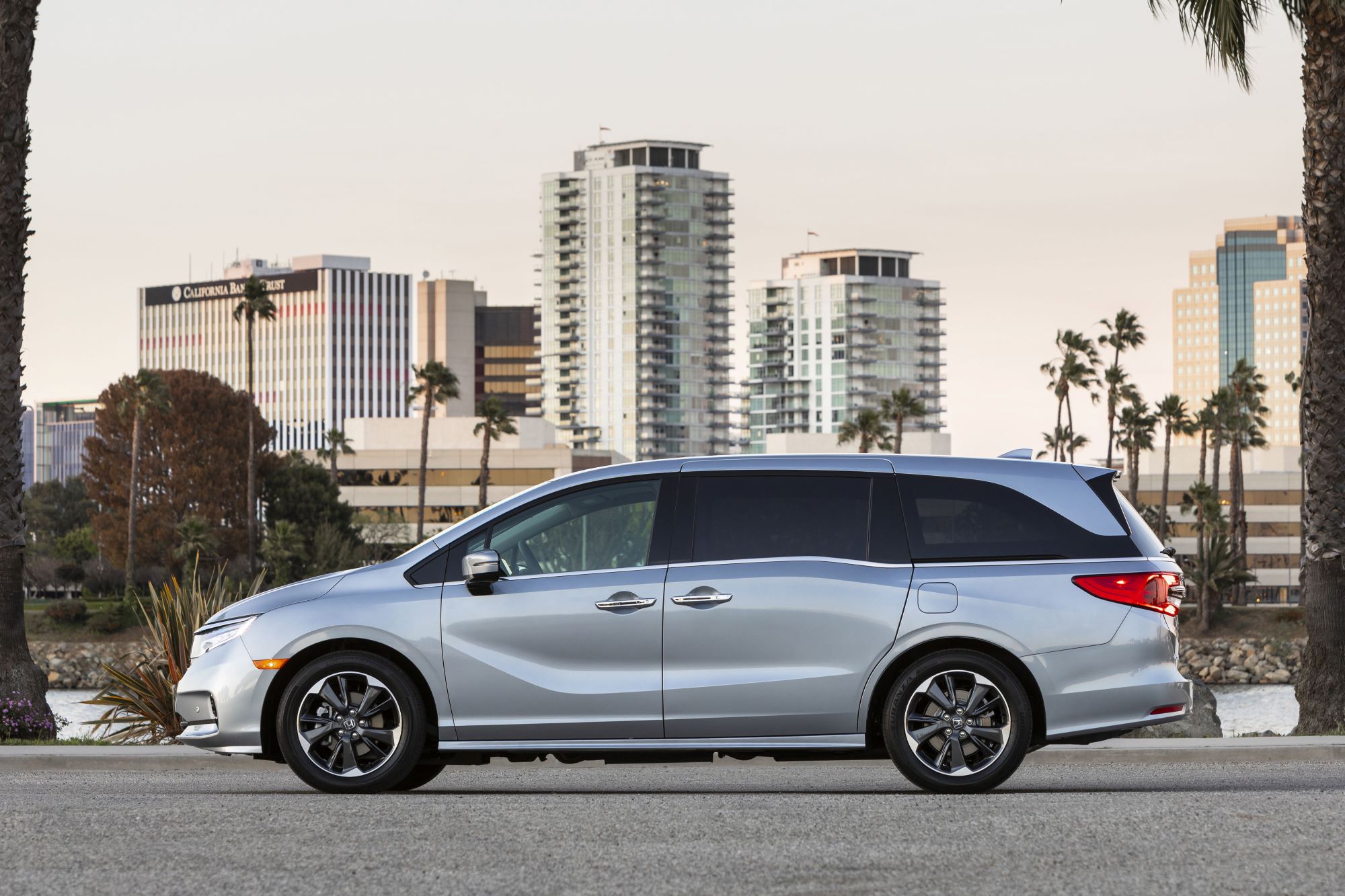 A silver Honda Odyssey in front of a city skyline.