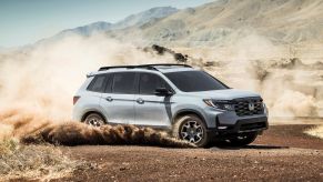 2022 Honda Passport Trailsport compact adventure SUV dirting through a dirt field and kicking up dust clouds