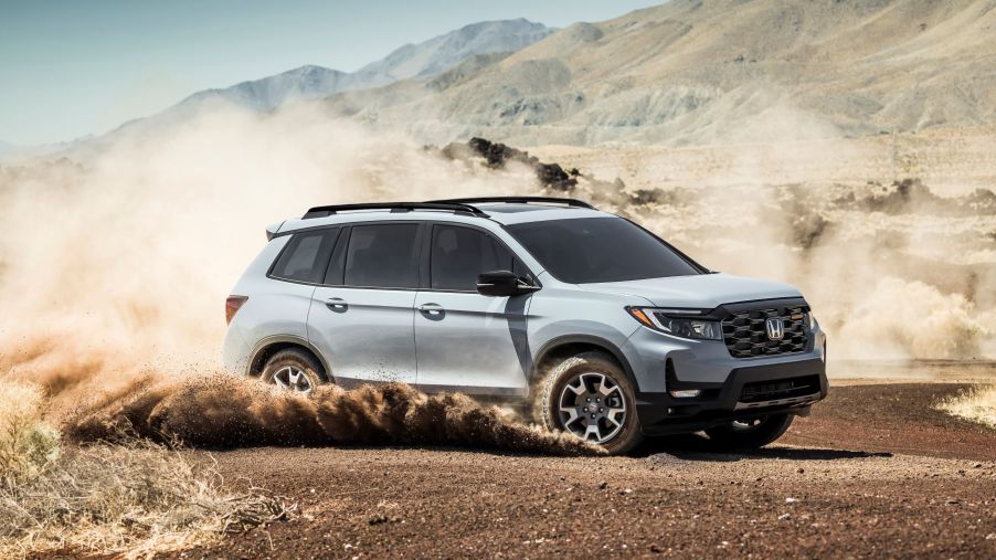 2022 Honda Passport Trailsport compact adventure SUV dirting through a dirt field and kicking up dust clouds