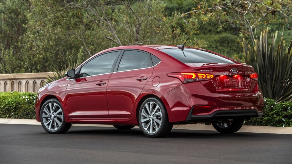 a red 2022 hyundai accent limited, stylish subcompact sedan, is parked along a garden bed
