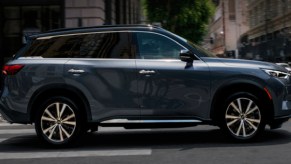 A gray 2022 Infiniti QX60 luxury SUV is driving on the road.
