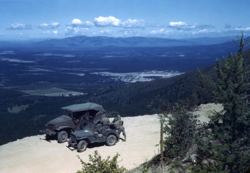 A Willys Jeep and Dodge truck parked on a mountain pass during a WW2 training exercies.