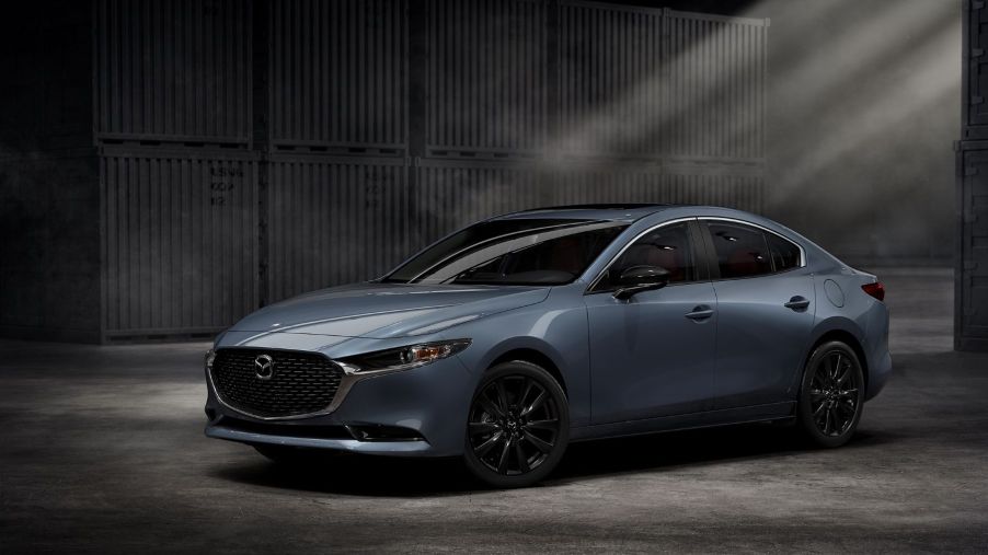 A 2022 Mazda3 compact sedan parked in an empty warehouse garage with light streaming in