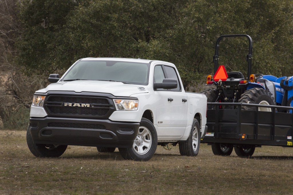 White Ram 1500 Tradesman pickup truck towing a tractor on a trailer.