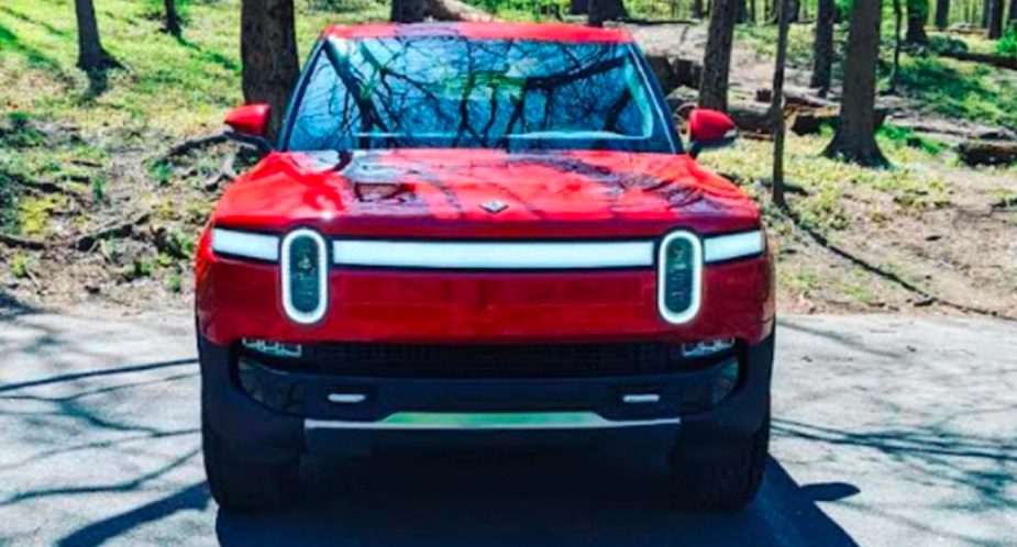 A red 2022 Rivian R1T Launch Edition electric pickup truck is pared on a sunny day.