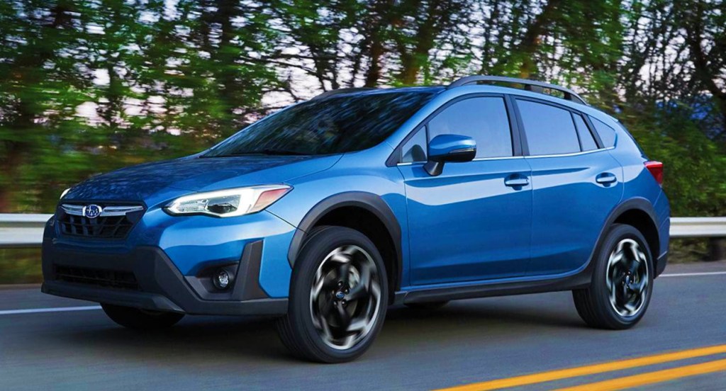 A blue 2022 Subaru Crosstrek subcompact SUV is driving on the road. 