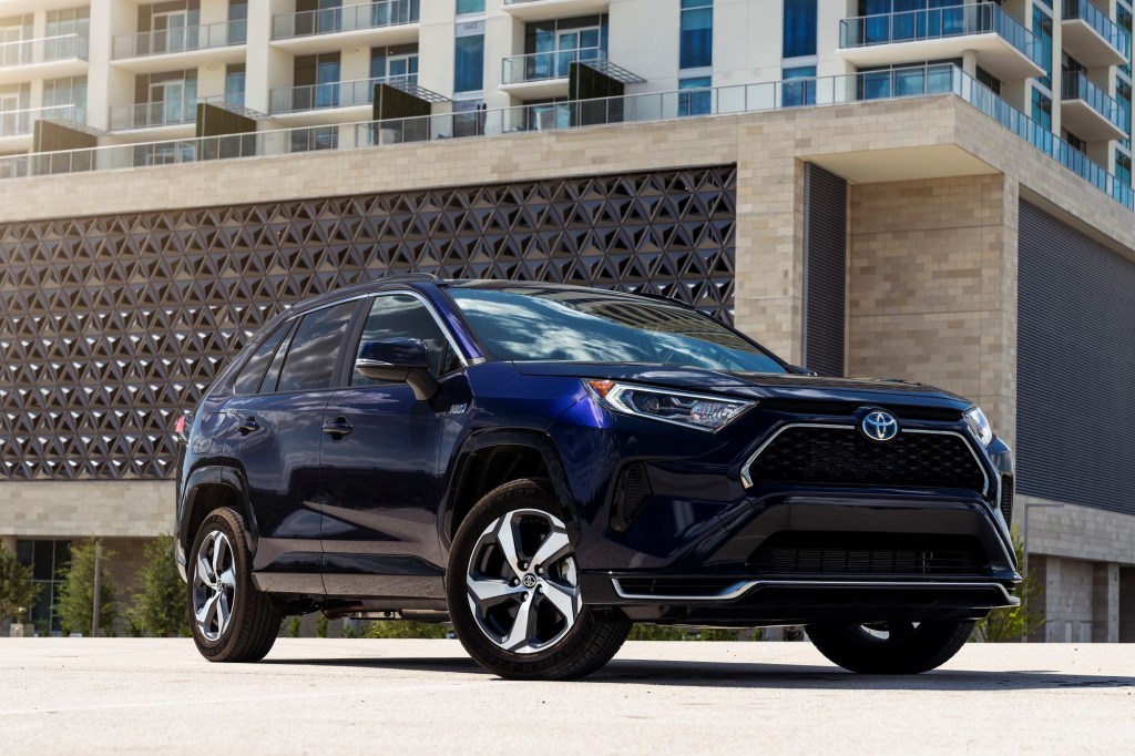 A blue 2022 RAV4 Prime sitting in front of a brown building.