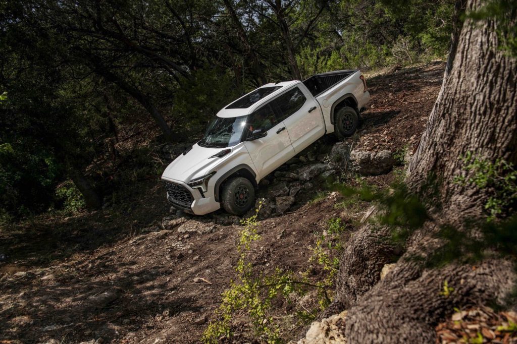 Toyota Tundra TRD Pro 4x4 truck navigating a steep obstacle on a trail through the woods.