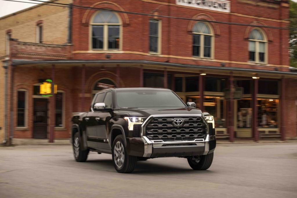 Promo shot of a brown Toyota Tundra pickup truck driving down a Main Street.