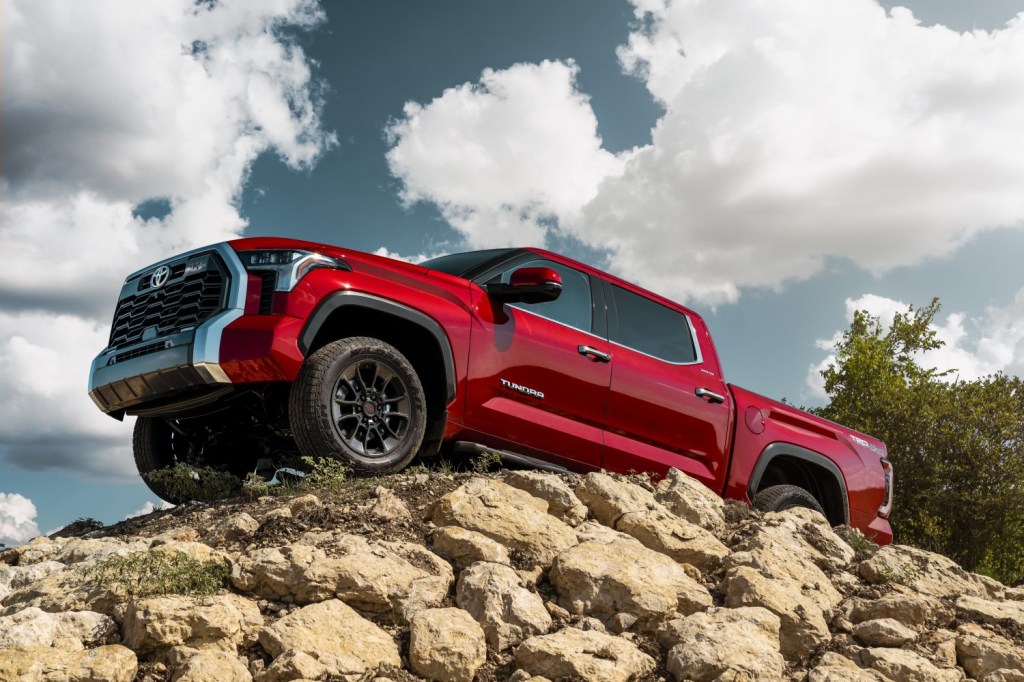 Publicity still of a red Toyota Tundra pickup truck parked atop a pile of rocks.