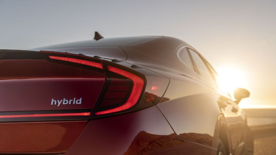 Close up view of the rear of a red 2022 Hyundai Sonata Hybrid fuel-efficient midsize sedan with the hybrid badge featured prominently