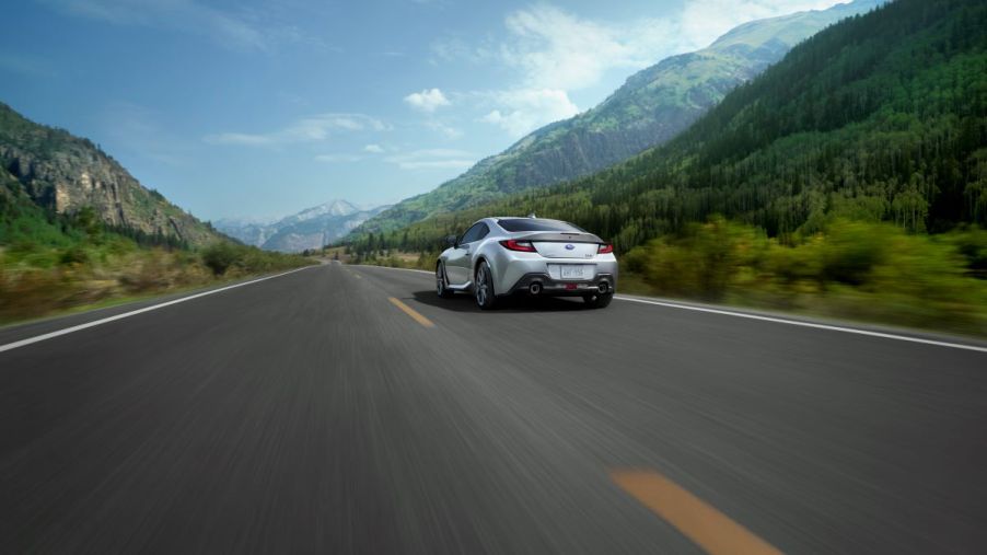 Backside of a silver 2022 Subaru BRZ, a Top Safety Pick Plus, driving away down a road with mountains on both sides
