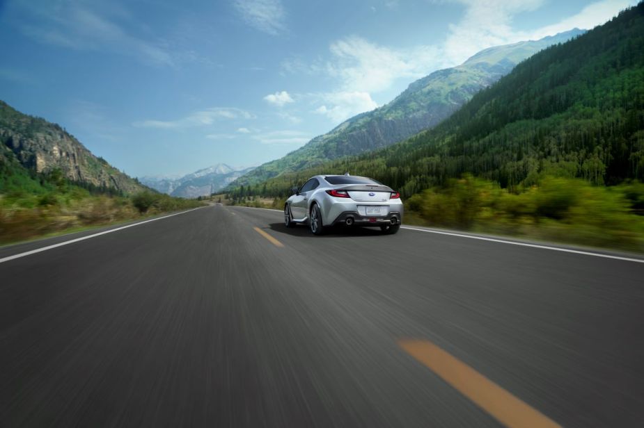 Backside of a silver 2022 Subaru BRZ, a Top Safety Pick Plus, driving away down a road with mountains on both sides