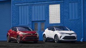 Two Toyota C-HR crossovers in front of a blue building