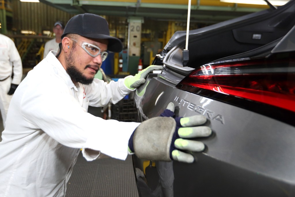 Factory worker at Honda's Maryville Auto Plant installs the Integra badge on an Acura sports car.