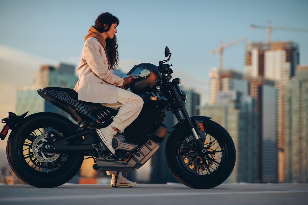 The side view of a white-clad rider on a gray-and-black 2023 LiveWire Del Mar Launch Edition in a city