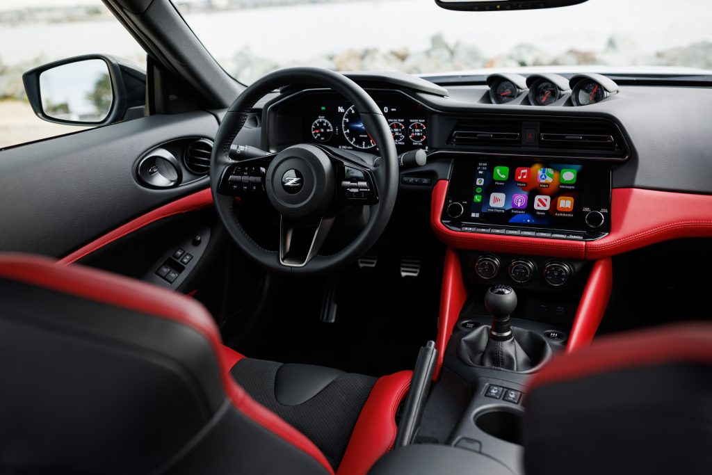 The black-and-red front seats and dashboard of a 2023 Nissan Z with a manual transmission