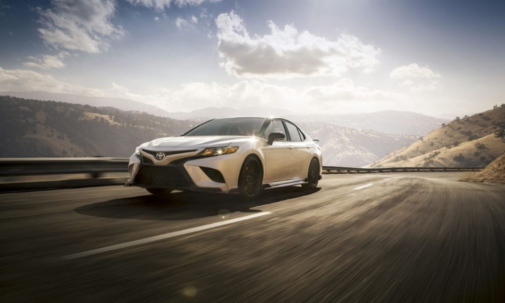 White Toyota TRD driving along a mountain road; the 2023 Camry midsize sedan will include a TRD variant