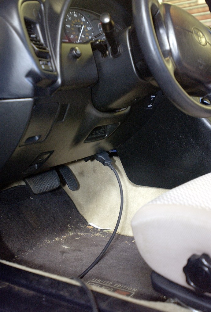An OBDII tool plugged into a car OBDII port during an emissions test