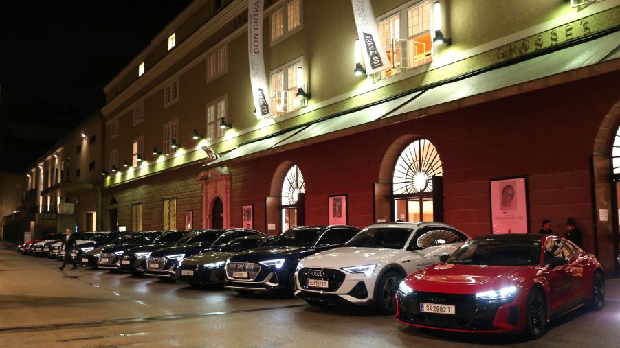 A row of Audi cars, potentially electric Audi vehicles, in a row in front of a well lit building.