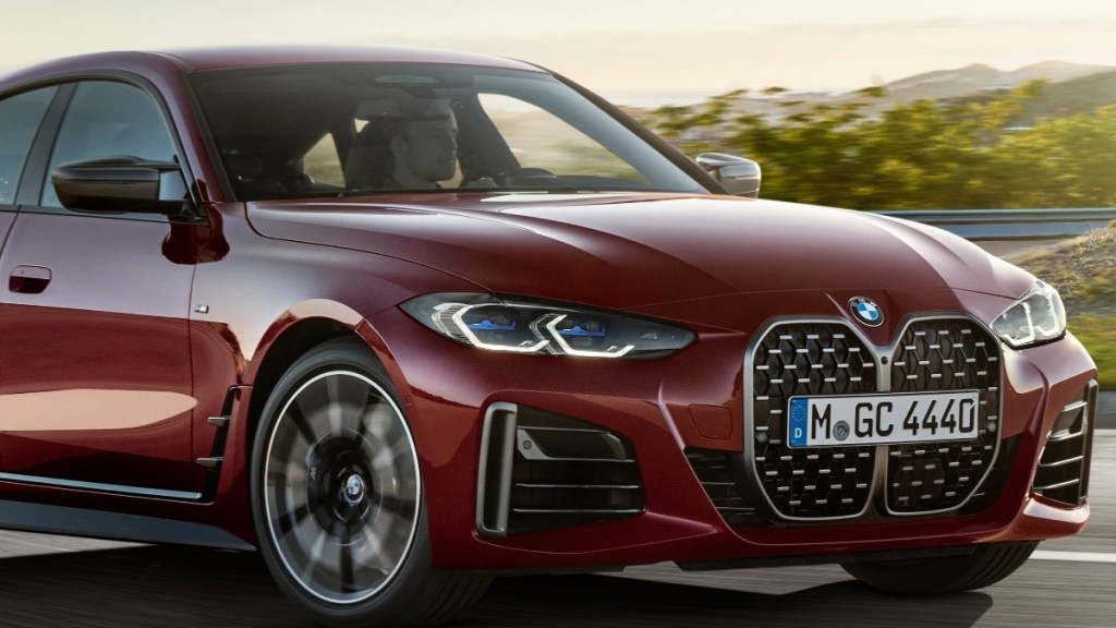 a red 2022 BMW M440i driving along a road at sunset showing off why its one of the top-sports sedans available