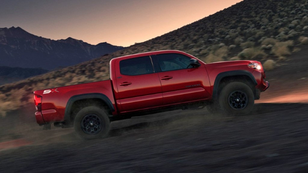 Barcelona Red Metallic 2023 Toyota Tacoma driving up a hill