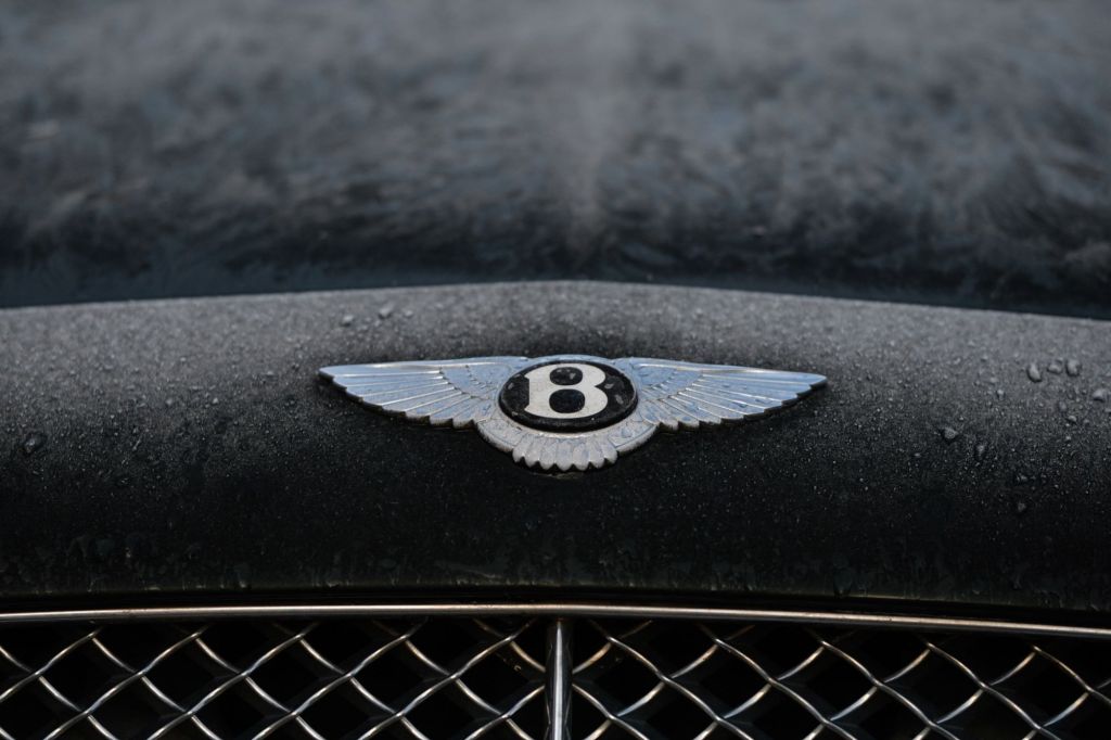 A Bentley logo on a black car, that may require a different license in Europe to drive. 