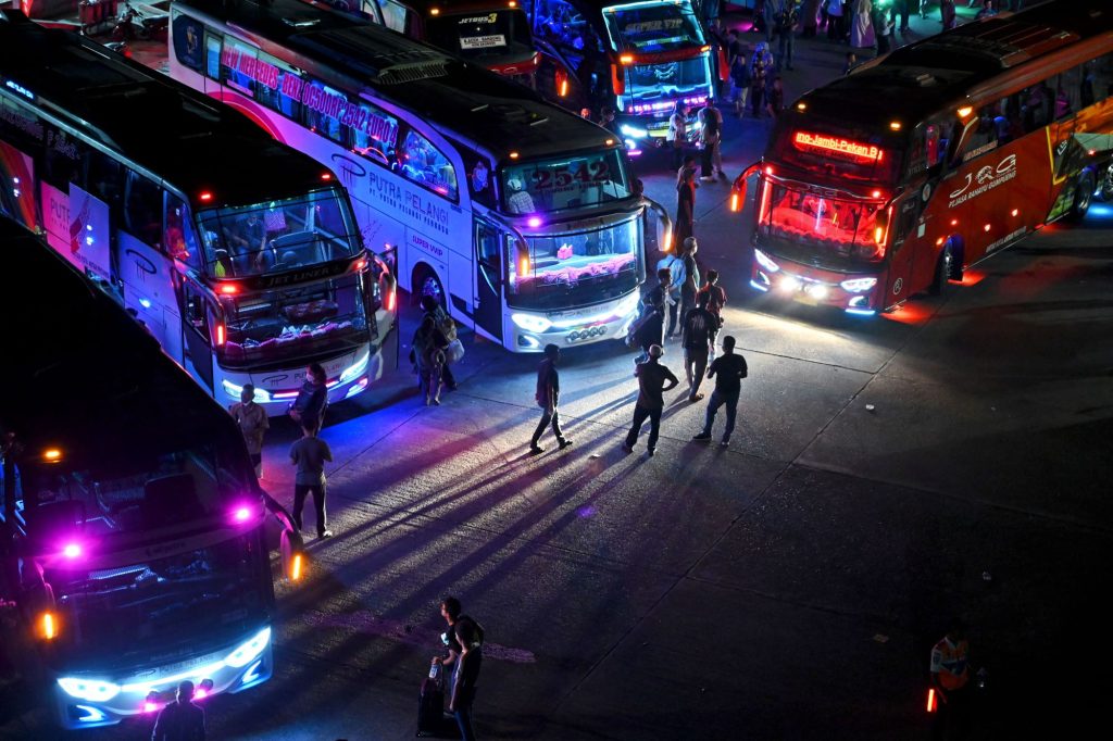A group of busses, potentially party busses gathered at night. 