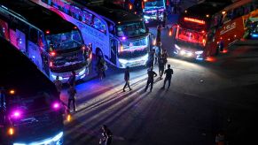 A group of busses, potentially party busses gathered at night.
