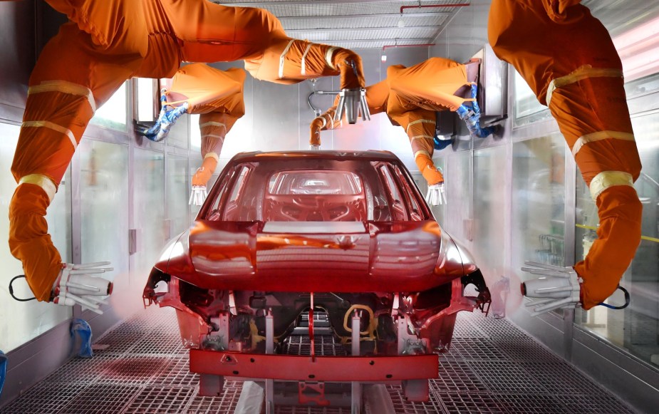 A car being painted red, that may potentially have paint protection on it when completed. 