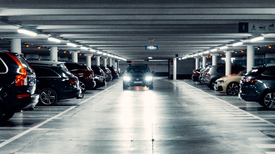 Car driving in a parking garage, highlighting a woman that angered neighbors by double parking in two spaces