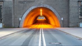 A stone car tunnel with amber lighters inside.