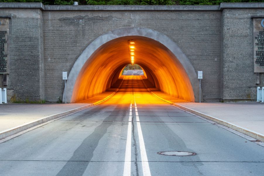 A stone car tunnel with amber lighters inside.