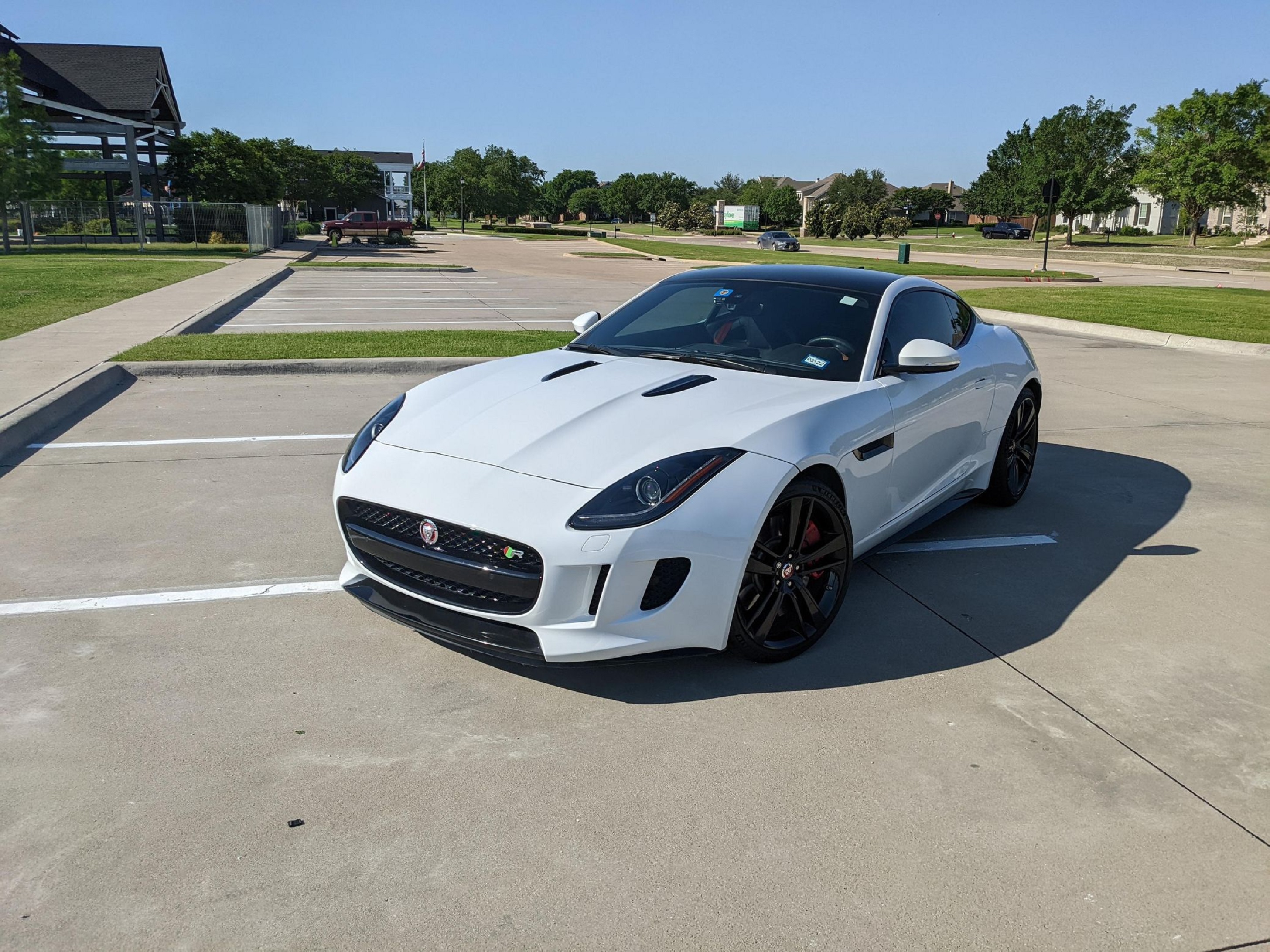 A ceramic-coated white 2015 Jaguar F-Type R Coupe in a sunny parking lot