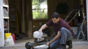 A person with the oil for lawn mower changing the oil.