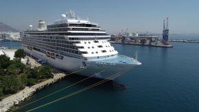 A large cruise ship on the water at dock.