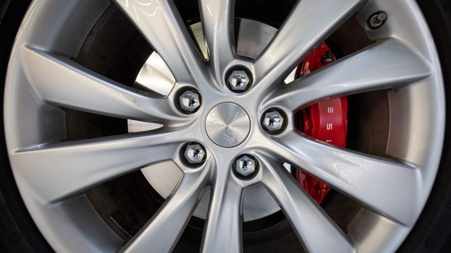 A close-up view of a Tesla Model X's disc brake and wheel during electric car maintenance