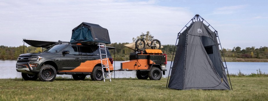 2022 Expedition Timberland parked near a lake with a tent and trailer