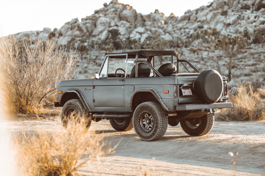 Gray first-generation Ford Bronco convertible SUV parked in the desert for a photo shoot.