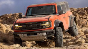 A red 2022 Ford Bronco Raptor off-road SUV is crawling rocks.