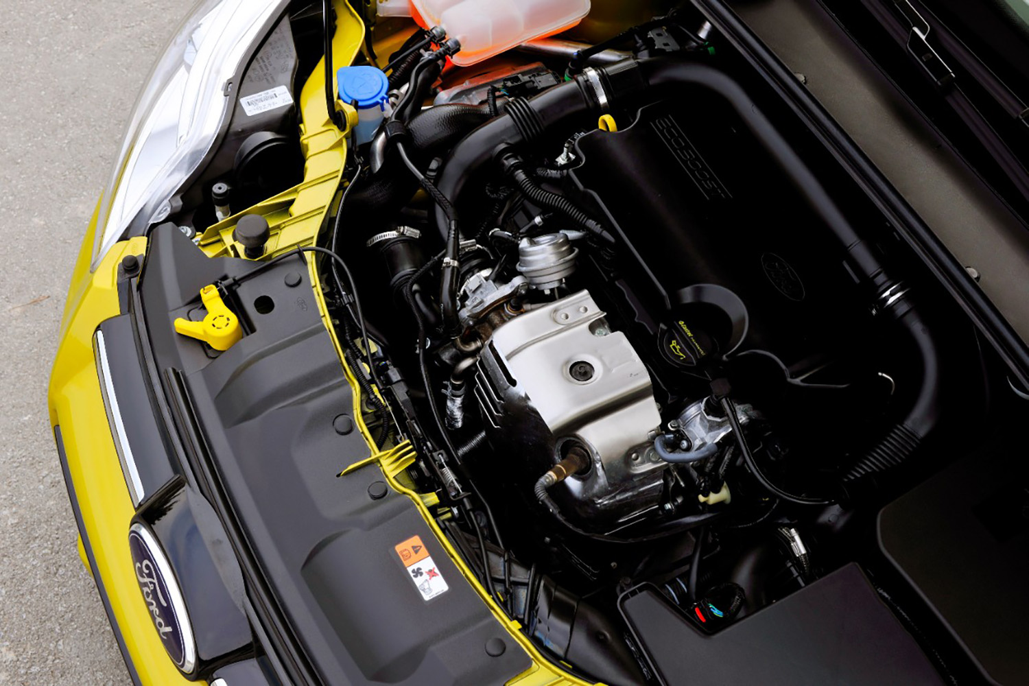 Engine bay of a lime green Ford Focus with 1.0-liter Ecoboost three-cylinder engine