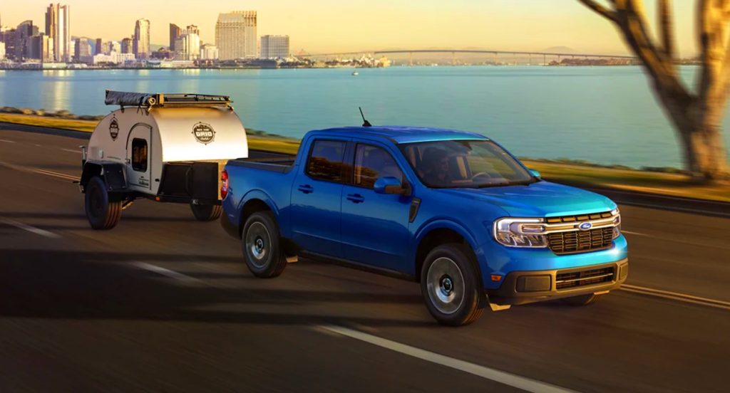 A blue 2022 Ford Maverick small pickup truck is towing a small trailer. 