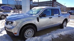 A silver Ford Maverick parked outside in front of a building surrounded by snow.