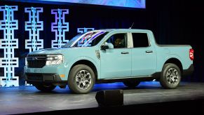 A mint green Ford Maverick with blue lights in the background.