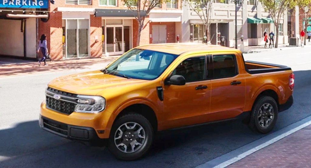 A yellow 2022 Ford Maverick compact pickup truck is parking on a sunny day. 