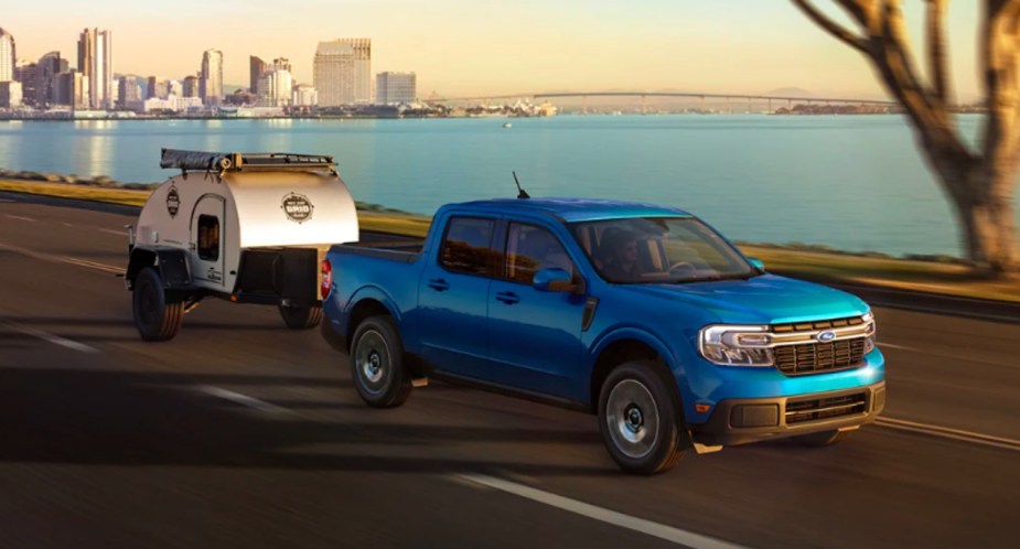 A blue 2022 Ford Maverick small truck is towing a small trailer. 