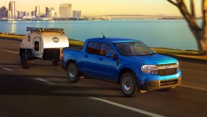 A blue 2022 Ford Maverick compact pickup truck is towing a small trailer.